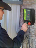 Rancher  connecting a patriot electric fence charger using a wall outlet on a stone wall