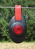 Patriot Red and black electric fence light-like device hanging on a wire with green trees in the background