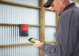 farmer with remote control for the Speedrite 46000W AC/Mains Energizer that is mounted to a barn wall