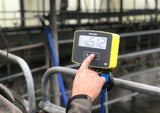 Tru-Test S3 Weigh Scale Indicator on metal railing at cattle farm with farmer operating it